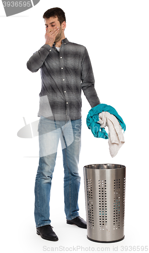 Image of Young man putting a dirty towel in a laundry basket