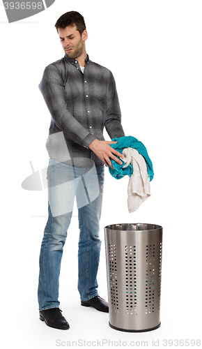 Image of Young man putting a dirty towel in a laundry basket