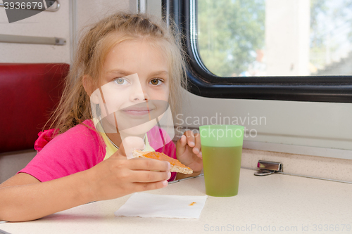 Image of Six-year girl drinking tea with a sandwich on the train at the table on outboard second-class carriage