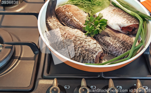 Image of Fish and components for her preparation in a large skillet.