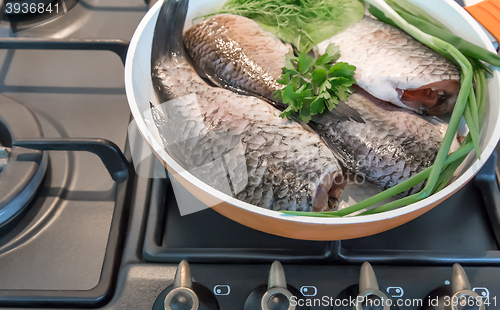 Image of Fish and components for her preparation in a large skillet.