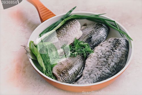 Image of Fish and components for her preparation in a large skillet.