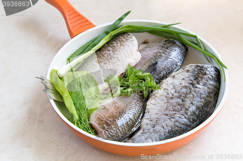 Image of Fish and components for her preparation in a large skillet.