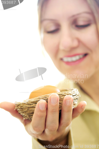 Image of Mature woman holding a nest with an egg