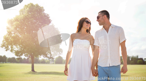 Image of happy smiling couple walking over summer park