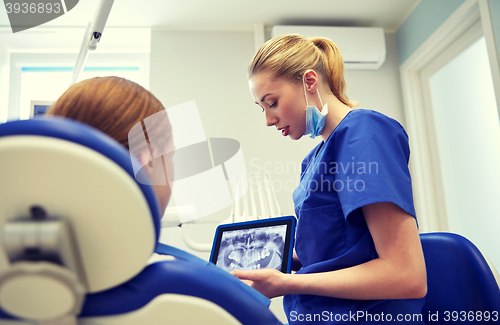 Image of dentist showing x-ray on tablet pc to patient girl