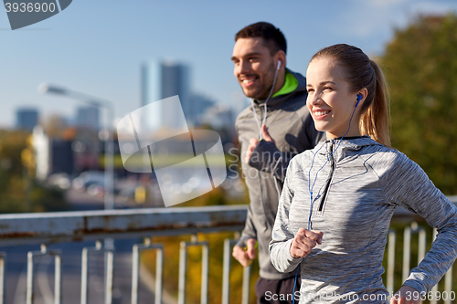 Image of happy couple with earphones running in city