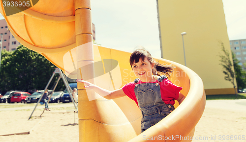 Image of happy little girl on slide at children playground