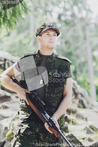 Image of young soldier or hunter with gun in forest