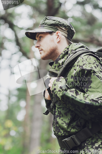 Image of young soldier with backpack in forest