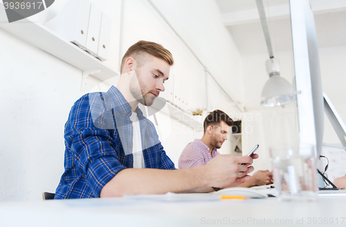 Image of creative man texting on cellphone at office