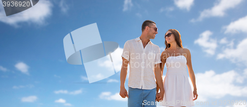 Image of happy smiling couple walking over blue sky