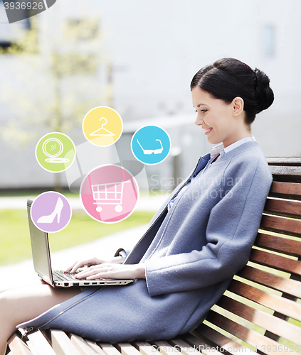 Image of smiling business woman with laptop in city