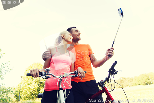 Image of couple with bicycle and smartphone selfie stick