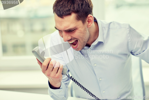 Image of furious businessman calling on phone in office