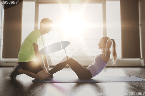 Image of woman with personal trainer doing sit ups in gym