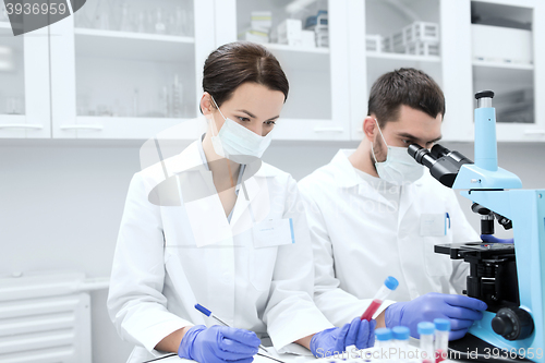 Image of scientists with clipboard and microscope in lab