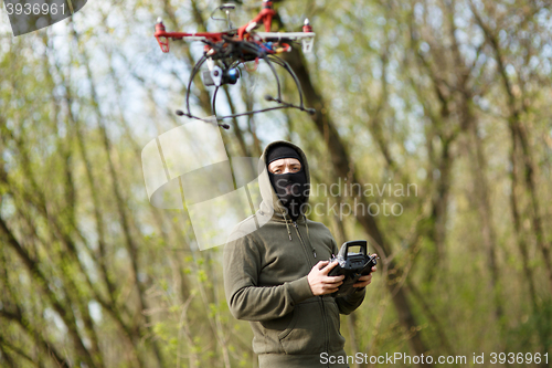 Image of Man in mask operating a drone with remote control.