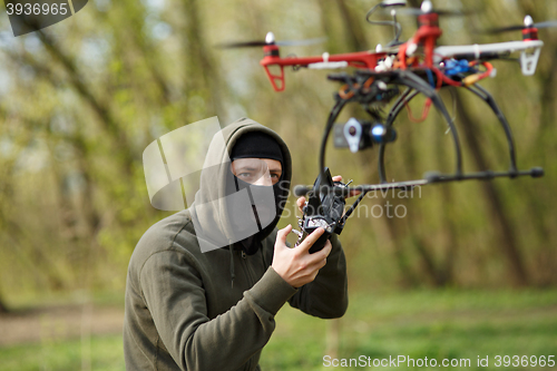 Image of Man in mask operating a drone with remote control.