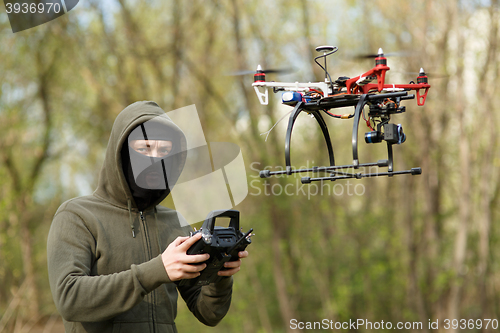 Image of Man in mask operating a drone with remote control.