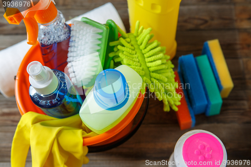 Image of Plastic bucket with cleaning supplies on wood background