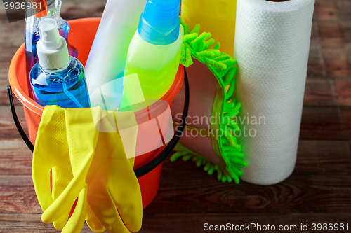 Image of Plastic bucket with cleaning supplies on wood background