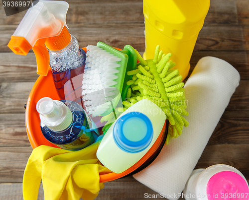 Image of Plastic bucket with cleaning supplies on wood background