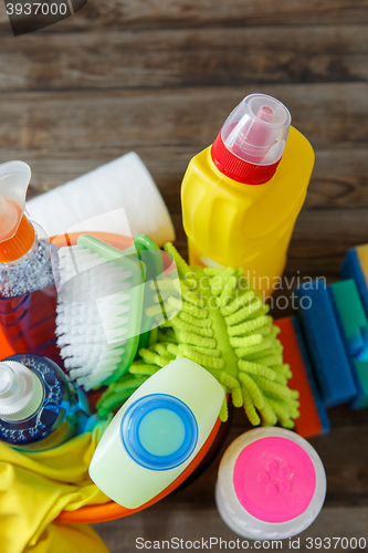 Image of Plastic bucket with cleaning supplies on wood background