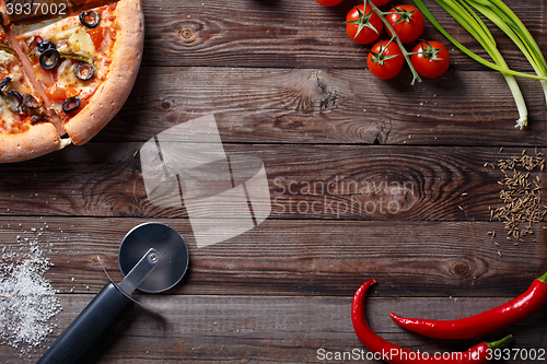 Image of Tasty pizza with ingridients on a wooden board.