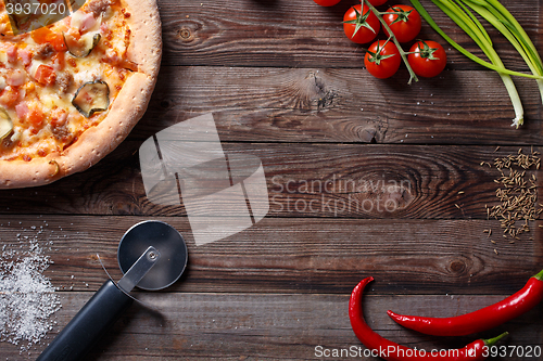 Image of Tasty pizza with ingridients on a wooden board.
