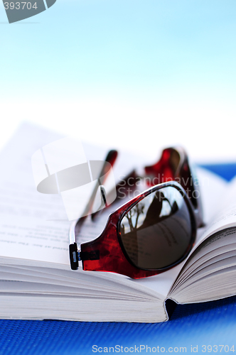 Image of Sunglasses and book on beach chair