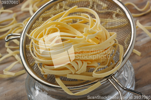 Image of Raw noodle pasta in metal kitchen sieve