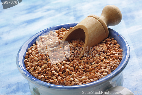 Image of Buckwheat seeds into ceramic cup with wooden scoop