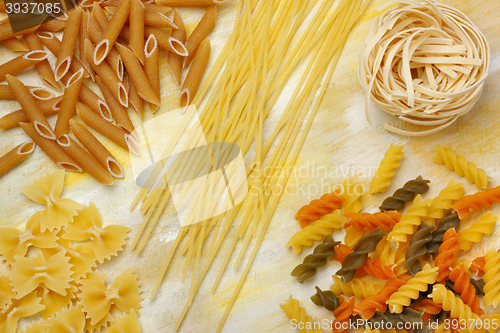 Image of Variety of dry raw pastas over painted textile background