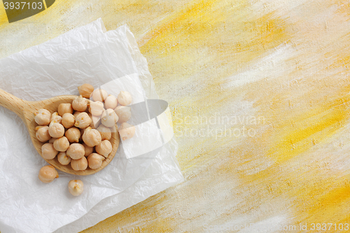 Image of Still life with chickpea seeds on wooden spoon and paper cloth