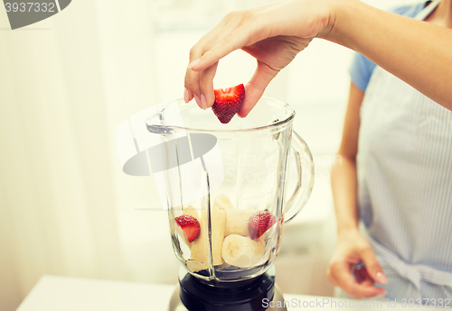 Image of close up of woman with blender making fruit shake