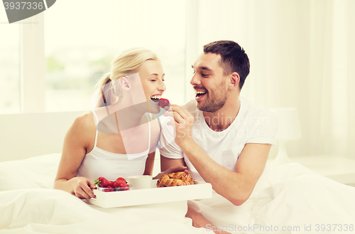 Image of happy couple having breakfast in bed at home