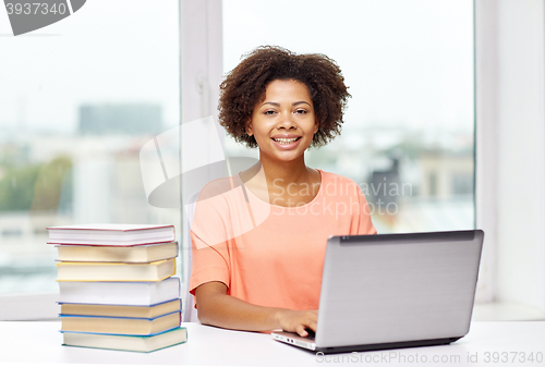 Image of happy african american woman with laptop at home