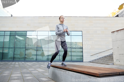 Image of woman making step exercise on city street bench