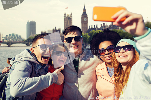 Image of smiling friends taking selfie with smartphone