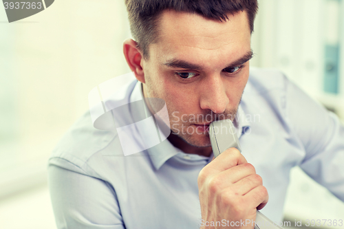 Image of face of businessman with phone receiver in office