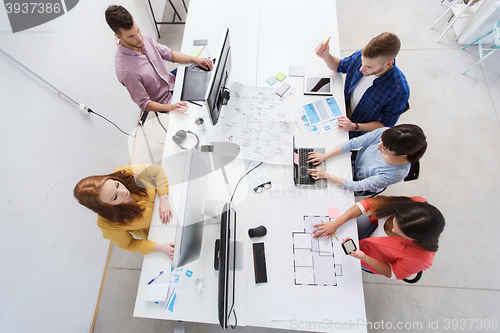 Image of creative team with computers, blueprint at office
