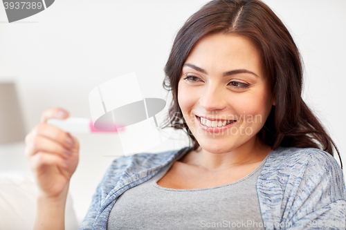 Image of happy woman looking at home pregnancy test