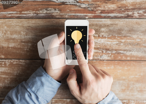 Image of close up of male hands with smartphone on table