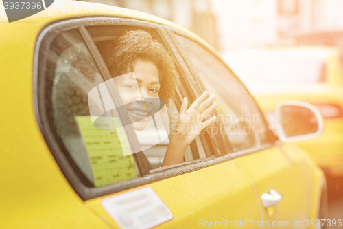 Image of happy african american woman driving in taxi