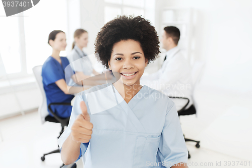 Image of happy female doctor or nurse showing thumbs up