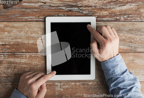 Image of close up of male hands with tablet pc on table