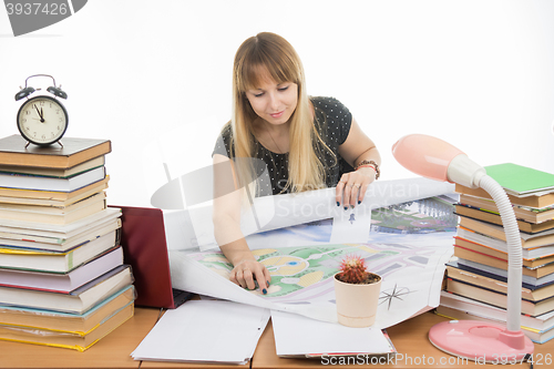 Image of Girl student studying design drawing master plan at a table cluttered with books