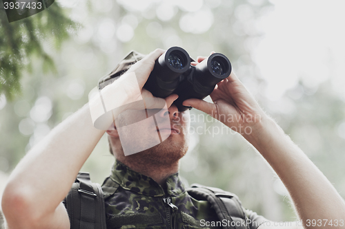 Image of young soldier or hunter with binocular in forest