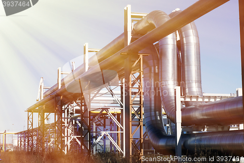 Image of industrial pipelines on pipe-bridge against blue sky